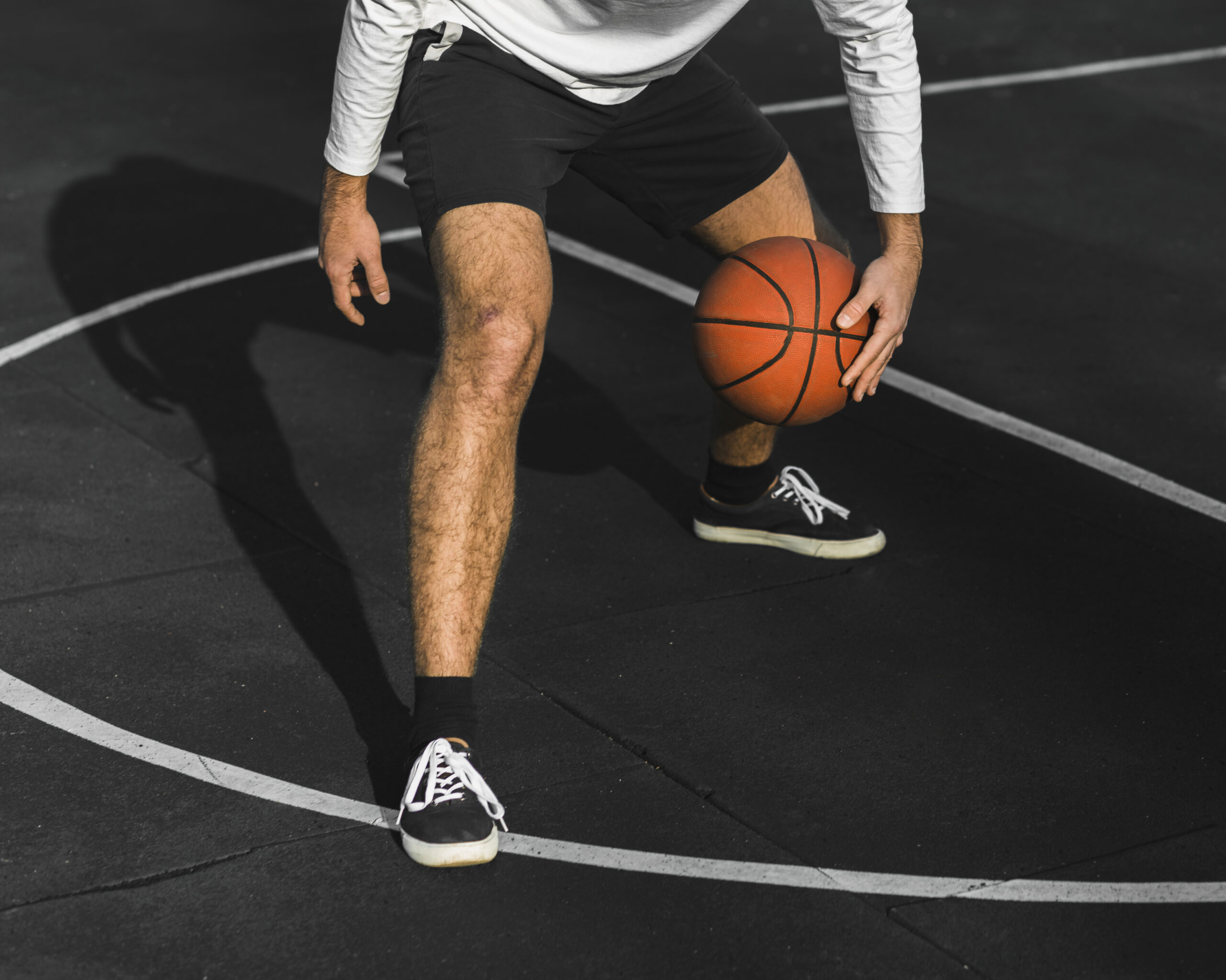 unrecognisable-man-bouncing-basketball-court